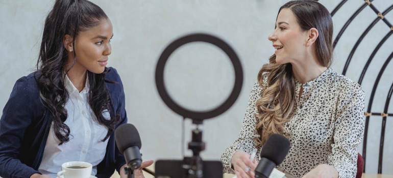 Two women sitting at a table and recording a video for social media