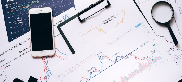 Magnifying glass and a smart phone on top of papers with Google Maps marketing tactics analytics