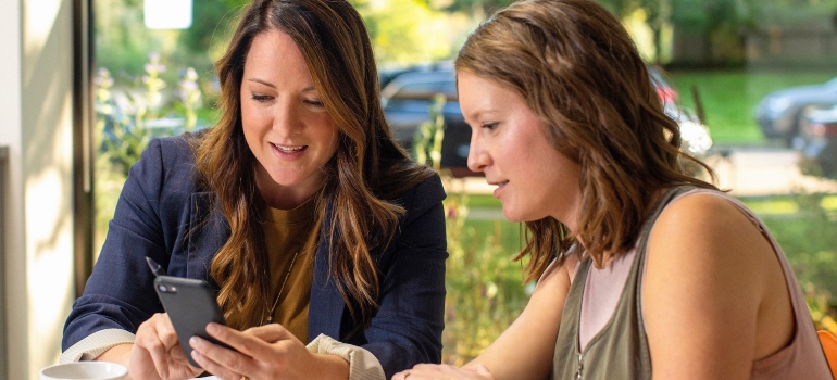 Two women researching digital marketing trends impacting the moving industry on a phone