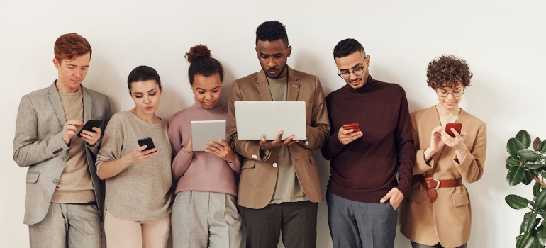 Group of people standing next to each other and researching SEO strategies for solar energy companies on different devices