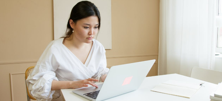 A woman browsing the internet on a laptop, illustrating how the dos and don'ts of alcohol rehab advertising must hinge on accurate information.