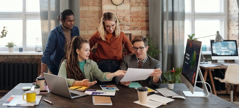 Marketing team in front of a laptop and discussing the differences between B2B and B2C social media marketing
