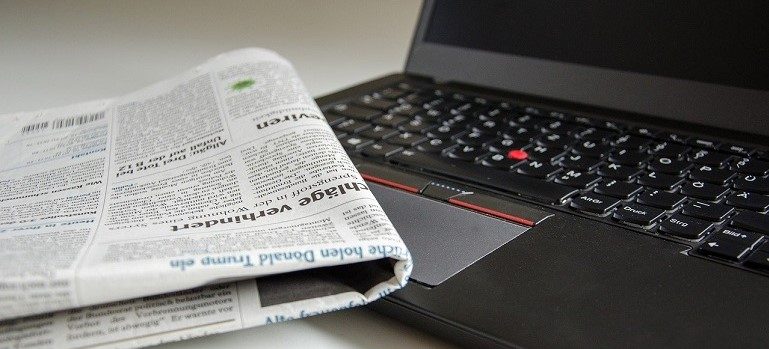 Newspaper next to a laptop