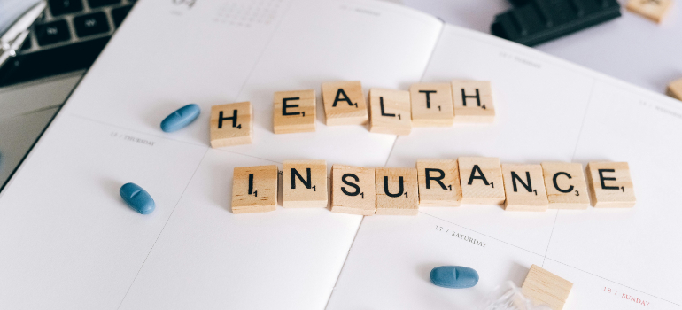 Tiles spelling out "HEALTH INSURANCE" on a paper calendar, a concept for content planning using health insurance keywords for rehab clinics.