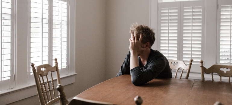 A man holding his head at a table 