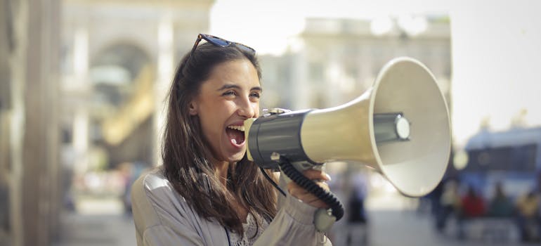 a woman enthusiastically speaking into a megaphone