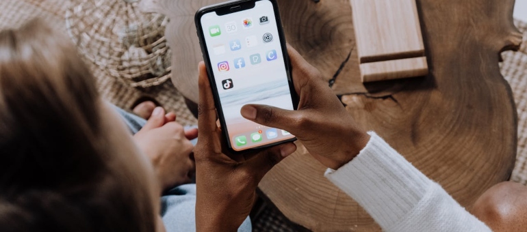 Two people sitting next to each other and browsing Instagram on a smart phone