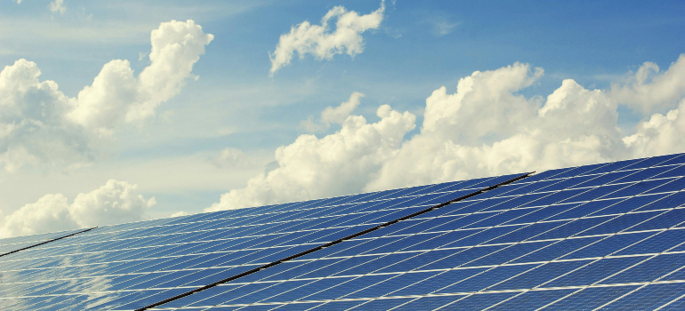 Solar panels under a bright sky with clouds, illustrating seasonal trends in solar marketing and the importance of adapting marketing strategies to peak seasons.