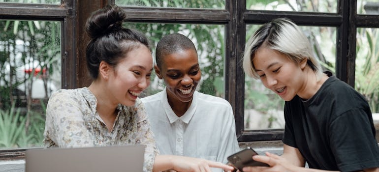 Three friends talking and looking at a smartphone