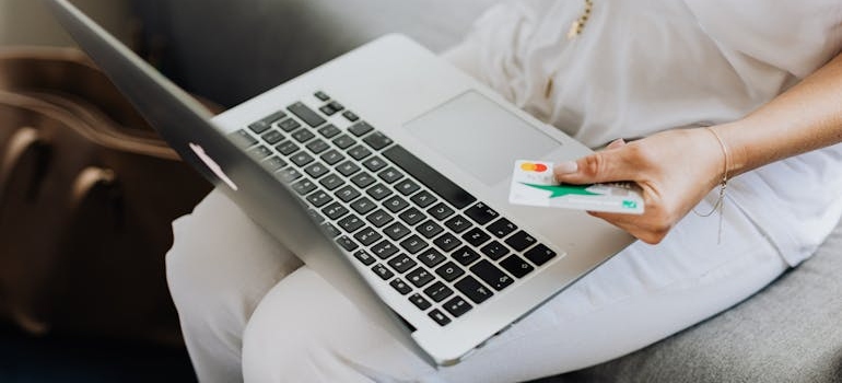 A person using holding a credit card while using a laptop