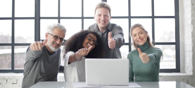 A marketing team showing their thumbs up