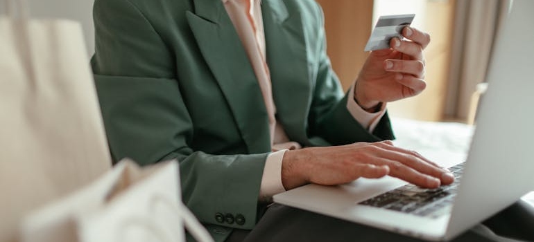 A person using a laptop and holding a credit card