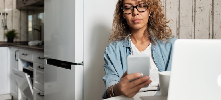 a woman holding a mobile phone in her hand and looking at it 