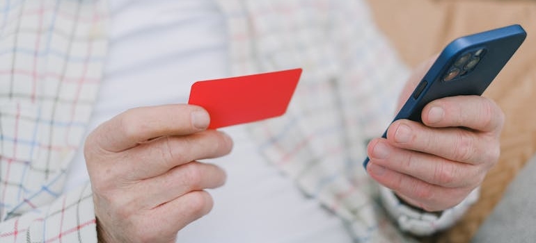 A person holding a credit card and a phone