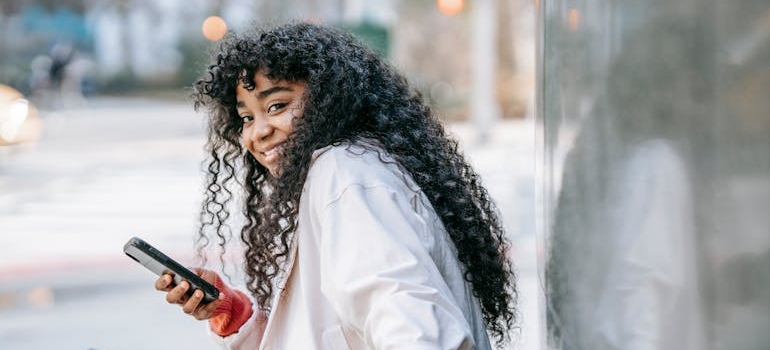 An adolescent smiling while using their phone