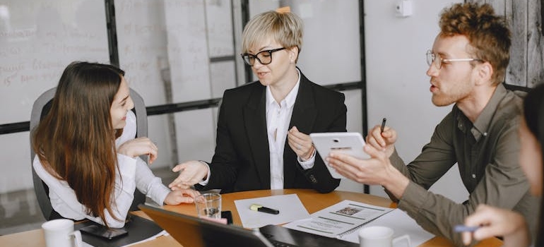 Three professionals having a discussion around a table in a modern office setting