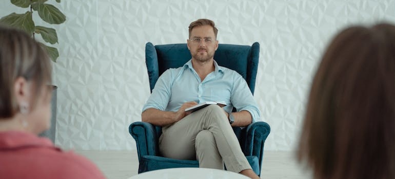 A therapist taking notes and listening to people during a therapy session