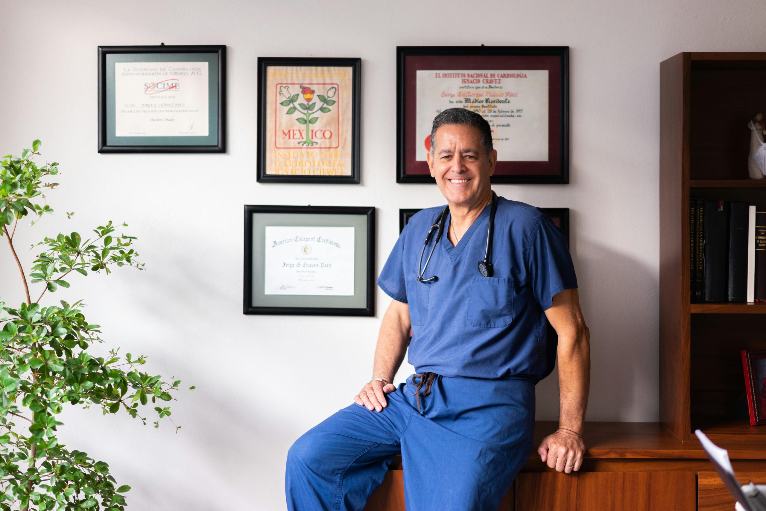 A doctor standing n front of a wall showing off his certifications.