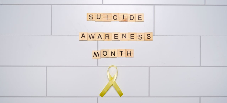 Suicide Awareness Month spelled with letter tiles and yellow ribbon
