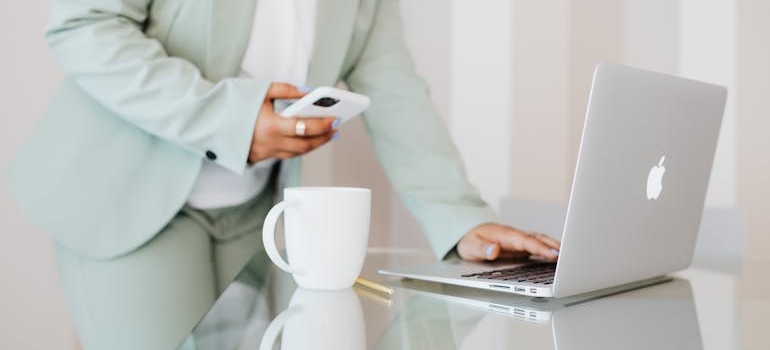 A person using a smartphone and a laptop