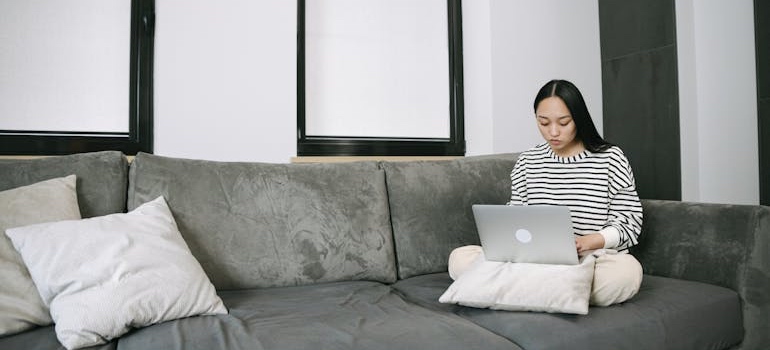 A person sitting on a couch and using a laptop to look for healthcare centers
