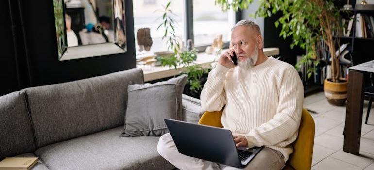 A person using a laptop and talking on phone